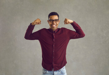 Young african american man showing strength and power with muscle hands studio shot. Business man with positive emotion face portrait. Black guy showing biceps. Leadership and confidence concept