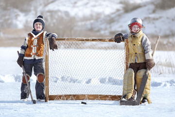 Children play hockey. Team of young boys are engaged in active winter sports on the ice of the lake against the background of a snow landscape on a sunny day. Art photography in retro style.