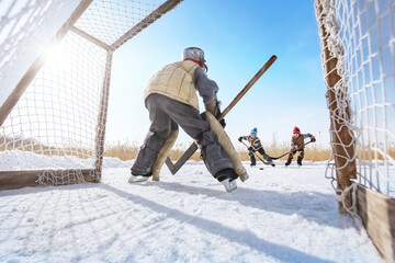 Children play hockey. Team of young boys are engaged in active winter sports on the ice of the lake...