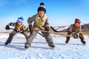 Children play hockey. Team of young boys are engaged in active winter sports on the ice of the lake...