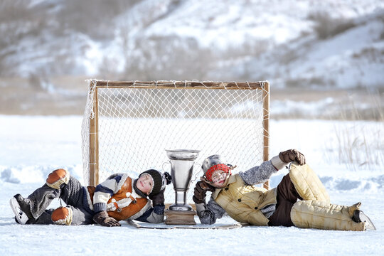 Children play hockey. Team of young boys are engaged in active winter sports on the ice of the lake against the background of a snow landscape on a sunny day. Art photography in retro style.