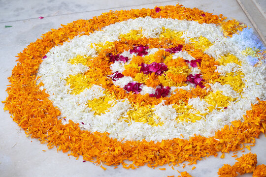Rangoli pookalam pattern made of flower petals on teh ground for religious celebrations like diwali, christmas and new year