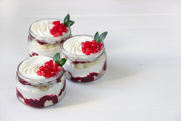 Berry trifles in a glass jars decoraited pomegranate, portion sweets on white background, berry cheesecake