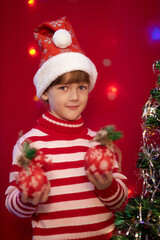 Christmas eve happy little girl in red striped pajamas decorates the christmas tree