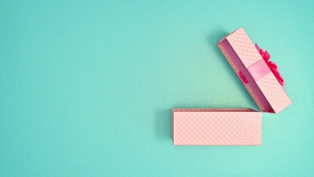 Pastel pink gift appear and open on cyan background. Stop motion