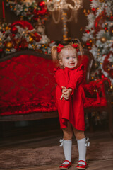 charismatic little girl in a red dress on the background of Christmas decorations	 