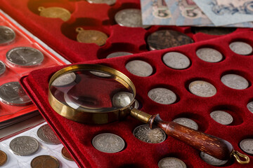 Numismatics. Old collectible coins made of silver on a wooden table.Coins in the album.Collection of old coins. Magnifying glass - obrazy, fototapety, plakaty