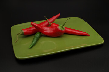 Chili peppers on plate over a black background