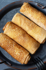 Thin pancakes or crepes stuffed with cottage cheese on grey background