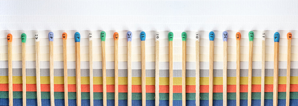 Multicolored matchsticks with faces painted on the heads on multicolored paper