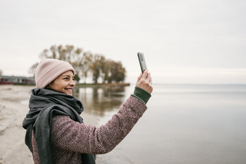 Smiling vivacious woman taking a selfie in winter
