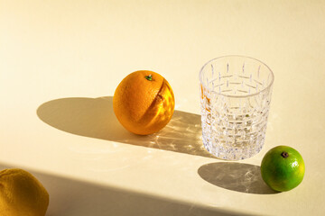 empty crystal glass under hard light, orange's, lime's and lemon's oval shadows, glitter reflection...
