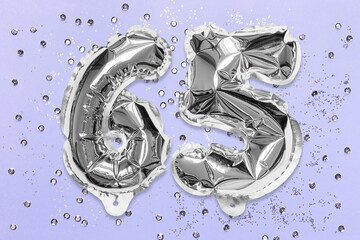 Silver foil balloon number, digit sixty five on a lilac background with sequins. Birthday greeting card with inscription 65. Anniversary concept. Numerical digit. Celebration event, template.