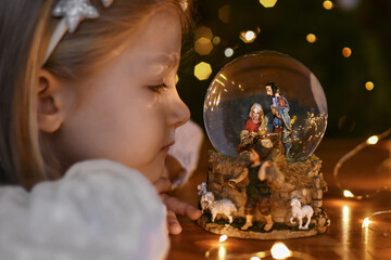 Girl looking at a glass ball with a scene of the birth of Jesus Christ