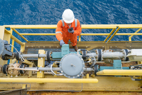 Electrical and instrument technician calibrating oil field instrument, Coriolis flow meter and actuated control valve on offshore oil and gas platform.