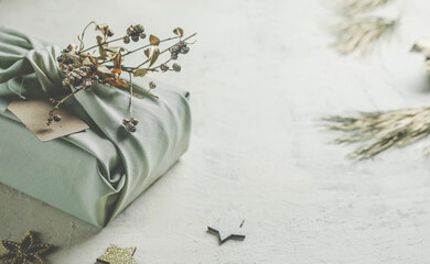 Christmas background with  sustainable gift packaging made with grey fabric and small branch....