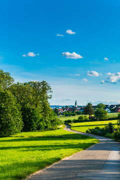 Germany, Beautiful nature landscape view and houses and church of village ostfildern kemnat behind curved way and green fields in summer