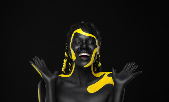 Woman On Poster With Gold Face Art. Yellow And Black Colors Of Body Paint. Young Girl With Bodypaint. An Amazing Afro American Model With Makeup.