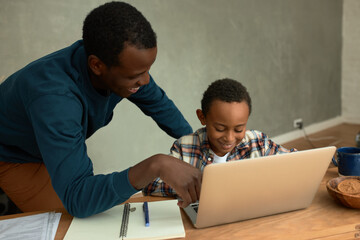 Human relationships. Dark-skinned uncle looking after his 8-9 years-old nephew, both laughing,...