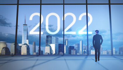 Businessman walking in office room, looking at New York panorama with 2022 icon
