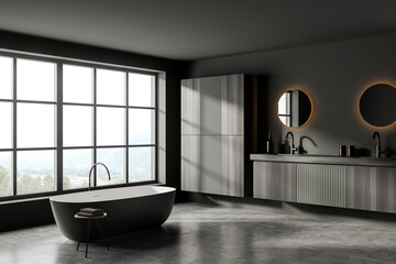 Dark bathroom interior with bathtub, sinks and mirror, window with countryside