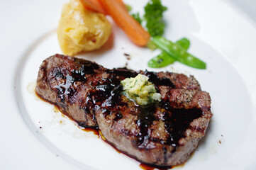 Grilled steak with mashed potato and black bbq sauce on white plate