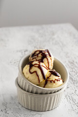 Vanilla ice cream  with caramel into the ceramic bowl on light background . Copy space