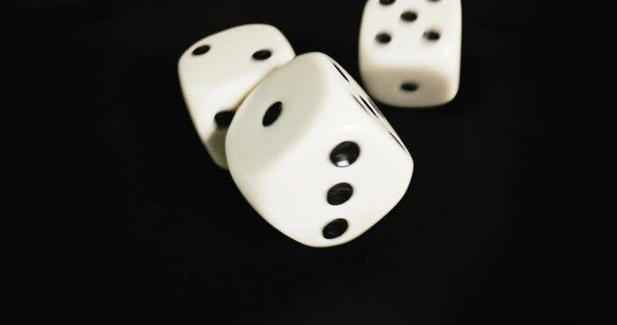 Plastic playing gambling dice rolling forever against dark background
