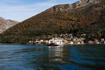 Fototapeta na wymiar Large ship sails to a town on the coast of the sea at the foot of the mountains