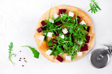 Pizza with roasted beet, feta cheese and arugula. Top view