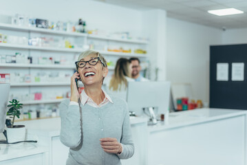 Smiling senior female patient in a pharmacy using smartphone