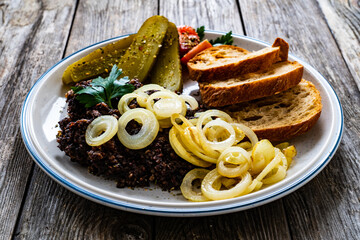 Fried blood sausage with onion and toasted bread on wooden table
