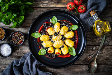 Gnocchi with tomatoes, parmesan, black olives  and basil on wooden table

