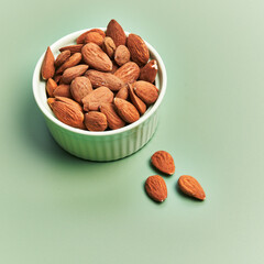 Bowl of delicious almonds over green background