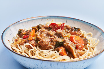  Plate of delicious spaghettis with meat and vegetables over blue background
