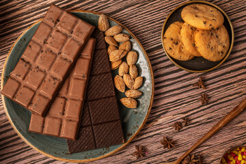 Chocolate bars with almonds, star anise and chocolate cookies and blue plate