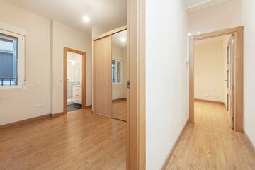 Empty furniture room with built-in wardrobe with large mirror door and separate toilet and view of hallway