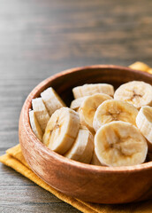 Photo of banana slices in a bowl on a wooden table