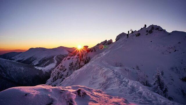 Sunset from the top of a snowy mountain. People move on top of the mountain. 