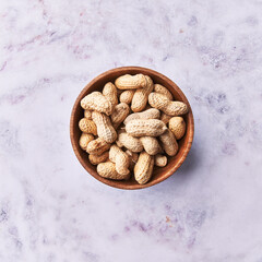  Bowl of peanuts with shell on a marble surface