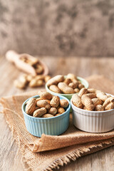  Bowls of peanuts with shell on a wooden surface
