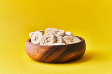  Bowl of slices of banana on a yellow background