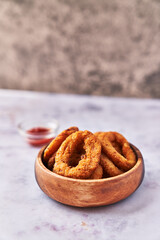  Bowl of breaded onion rings on a marble surface