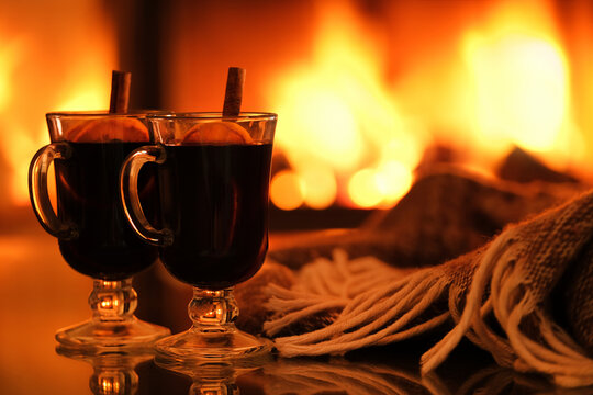 Two glasses with mulled wine and plaid on the fireplace background. Close-up. Background with text space.