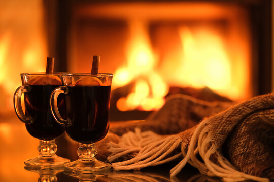 Two glasses with mulled wine and plaid on the fireplace background. Romantic concept. Background with text space.