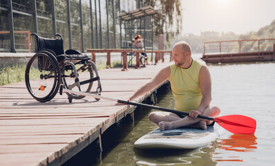 Person with a physical disability ride on sup board - obrazy, fototapety, plakaty
