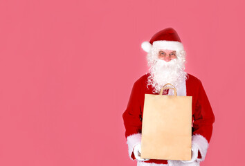 Santa Claus is smiling happily with shopping bags, with purchases and gifts at Christmas sales. Big Christmas sale. Isolate on a pink background