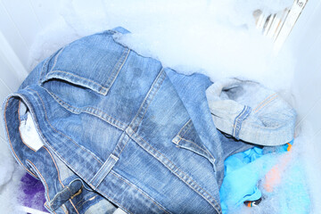 Washing a variety of clothes, including jeans, thoroughly with detergent to remove dirt and sweat...