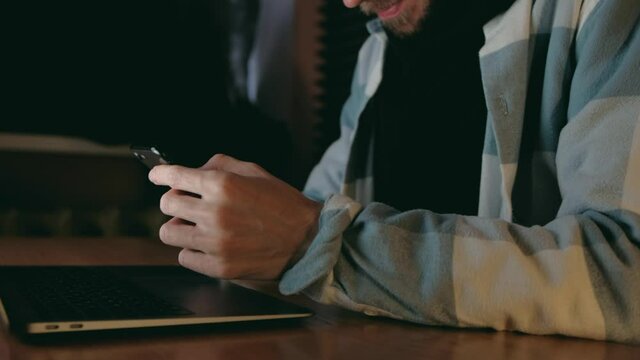 Hands of Man Freelancer Working at evening use smartphone and notebook. Close up. 4k. Male at workplace typing and Scroll phone.