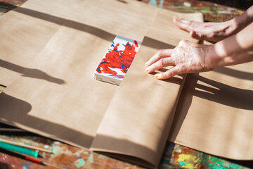 Woman wrapping her drawing at the paper while making present for somebody